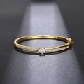 Primer plano del brazalete cruzado dorado con circón central y detalles pavé - Dorado