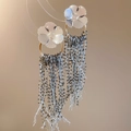 Detailansicht der Blumen-Ohrstecker mit langen dunkelgrauen Perlenquasten und Gold-Details - Silber