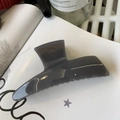 Detail view of a translucent dark grey hair claw clip with a glossy finish on white paper - Light Silver Grey