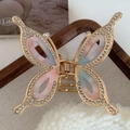 Detailed macro of a rhinestone butterfly hair claw with gradient wings and gold alloy frame - Sakura Pink