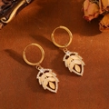 Detailed view of gold leaf earrings with beige cat eye stone and diamonds on brown suede - Gold White Stone Leaf Hoop Earrings