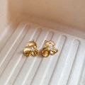 Detail von Blumenohrsteckern mit Gold-Finish und zentraler Perle auf weißem Tablett - Gold