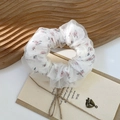 Detail eines geblümten Organza-Haargummis mit doppellagigem Mesh auf dekorativem Holzbrett - Floral Muster Rosa