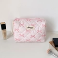 Close-up of pink quilted fabric makeup bag with cute bow patterns and zipper closure - Pink Bowknot