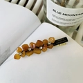 Amber acetate flower hair clip with rhinestones and handmade lettering on a white book - Brown