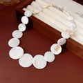 Detalle de collar de concha geométrica con perlas blancas y cierre de plata en caja de joyas - Blanco