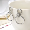 Chique zilveren drievoudige geometrische oorringen op een witte keramieken beker - Multi-Ring Nesten / Zilver