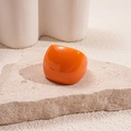 Detail of a bright orange chunky resin dome ring placed on a textured stone display - Orange