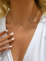 Dettaglio di una collana dorata con mini ciondoli rotondi lucidi indossata da una modella - Rotondo / Oro