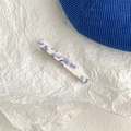 Detail shot of the blue and white marble textured acetate hair clip on textured fabric - Large Rectangle Duckbill Clip