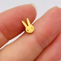 Macro shot of a tiny gold bunny stud earring held between fingers for scale - Rabbit / Gold