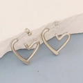 Macro shot of silver hollow heart-shaped earrings on a textured stone display - Silver Style K7-59