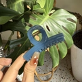 Elegant blue jelly texture claw clip with gold spring shown in hand for women - Haze Blue