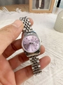 Detail of silver steel watch band with pink dial and calendar window held in hand - Purple