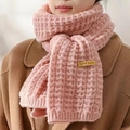 Detail of pink knitted scarf with 'hand made' label on camel coat for winter warmth - Pink Label Scarf