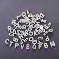 Close-up of polished silver metal alphabet beads with oval holes for DIY jewelry making - Large White K Mixed Color Perforated Letters Plated