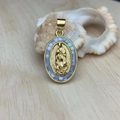 Macro shot of oval gold Virgin Mary pendant with inlaid mother of pearl on wood surface - Blue