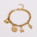 Detail of gold ocean-themed bracelet with starfish, seashell and conch charms on white backdrop - Gold