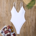 Flat lay of white deep V-neck one-piece swimsuit with beach accessories on wood background - White