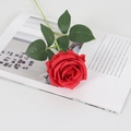 Single red velvet artificial rose with green leaves on an open magazine - Silk Dark Red