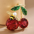 Detailed view of cherry and bee brooch with red gems, green enamel leaves and pearl body - Red