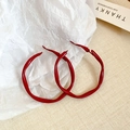 Detailansicht großer roter gedrehter Creolen auf strukturiertem Stoff und Papier - Gedrehtes Welliges Rot - Set 4.8cm+4.2cm (Silbernadel)