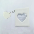 Close-up of a white photocard album with a heart-shaped cutout and matching charm - Jelly White