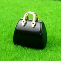 Miniature black crystal handbag pendant with golden handle on green grass - Obsidian