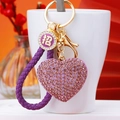 Close-up of purple rhinestone heart keychain with gold hardware and woven rope on a cup - Dark Purple Fortune Rope + Purple Heart