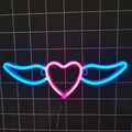 Pink heart and blue wings LED neon sign glowing on a black metal grid wall - Pink Heart + Blue Wings
