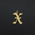 Macro shot of a gold-plated stainless steel letter X pendant charm on black textured surface - Letter X