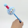 Close-up of blue fuzzy monster plush pen with large eyes and colorful antenna - Blue