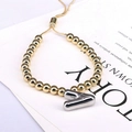 Detail of adjustable gold beaded bracelet with silver letter A charm and slider clasp - Letter V