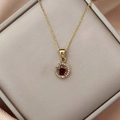 Detail of gold necklace with round red gemstone pendant surrounded by white zircon crystals - Gold Dark Red Zirconia