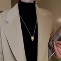 Close-up of a minimalist gold oval pendant necklace worn on a black turtleneck sweater - Gold Oval Style (12#)