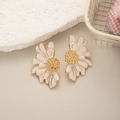 Detail of French vintage daisy earrings with white petals and golden core on a beige stone - White Daisy