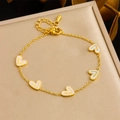 Goldenes Armband mit fünf weißen Herzanhängern und Karabinerverschluss auf Schmuckbox - Einzelnes Armband