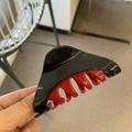 Detail of a two-tone black and red triangle hair claw clip in a glossy plastic finish - Black Red Patchwork