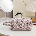 Close-up of quilted floral cosmetic bag with red flowers and a side handle strap - Handheld Red Floral