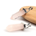 Polished rose quartz hexagonal prism pendants with silver metal clasps on wood - Rose Quartz