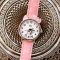 Close-up of pink girls cartoon quartz watch with kitten dial on a silver textured tray - Pink