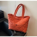 Close-up of quilted orange tote bag with front pocket and monthly topic magazine - Orange