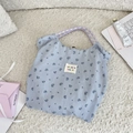 Dettaglio borsa shopper floreale con motivi blu e manici in corda viola su tappeto - Rose Blu