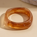 Detailed macro shot of an amber acrylic resin bangle with a thick geometric texture - Light Coffee