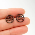 Close-up of minimalist black matte hollow mountain and sun stud earrings being held - Black