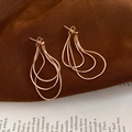 Macro shot of gold layered drop earrings featuring delicate snake chain tassels - Gold