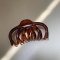 Dettaglio molletta per capelli leopardata con luce naturale e ombre su piano bianco - Rosso Leopardato