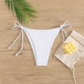 Flat lay of white tie-side bikini bottoms with adjustable bows on wooden background - White