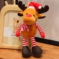 Peluche di renna natalizia con cappello rosso e sciarpa a righe su sfondo di legno - Stile Renna a Strisce / Altezza Seduta 13cm
