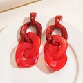 Detail of red acrylic chunky chain link earrings on white ceramic plate with soft lighting - Red